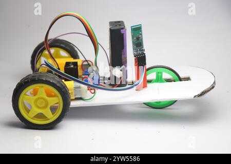 Kleines Roboterauto mit Mikrocontroller und bluetooth-Technologie, die über ein Smartphone auf weißem Hintergrund gesteuert wird Stockfoto