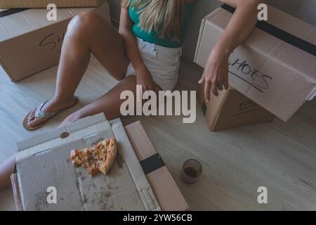 Eine Frau sitzt auf dem Boden mit Pizzaschachteln. Neues Hauskonzept. Stockfoto