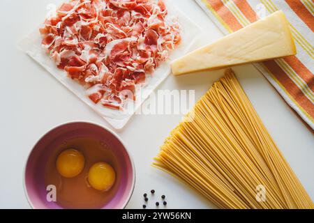 Zutaten für Carbonara Pancetta, Eier und Spaghetti auf weißem Hintergrund, Draufsicht Stockfoto
