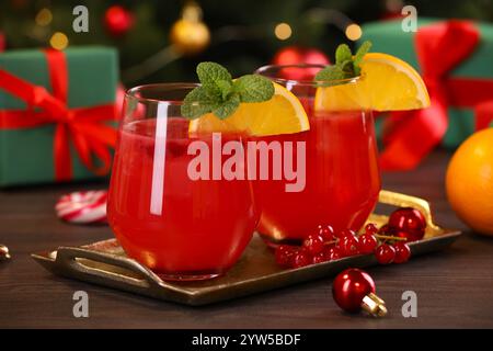 Weihnachtscocktail in Gläsern mit Zitrone und Johannisbeeren auf Holztisch, Nahaufnahme Stockfoto