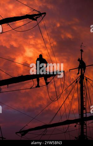 Crew eines großen Schiffes auf der Takelage bei Sonnenuntergang Stockfoto
