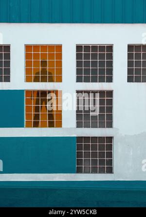 Mann, der hinter einem Fenster in einem Industriegebäude steht. Stockfoto