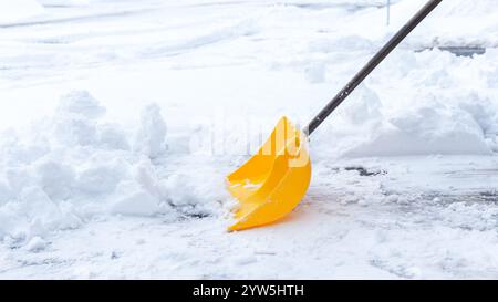 Mann schaufelt Schnee von seiner Auffahrt nach einem Wintersturm in Kanada. Mann mit Schneeschaufel reinigt im Winter Gehsteige. Winterzeit Stockfoto