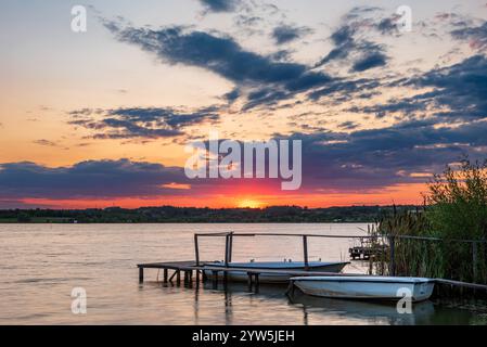 Zwei Fischerboote neben einem hölzernen Pier bei Sonnenuntergang auf dem Paljuvi-See in Serbien. Stockfoto