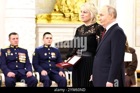 Moskau, Russland. Dezember 2024. Der russische Präsident Wladimir Putin vergibt posthum die Goldstermedaille an den Helden von Russland, den Freiwilligen Wladimir Gavrilenko, der seine Witwe Jelena Gavrilenko, links, während einer Zeremonie zum Tag der Helden des Vaterlandes in der Halle des Großen Kreml-Palastes am 9. Dezember 2024 in Moskau, Russland, entgegennimmt. Quelle: Alexander Kazakov/Kreml Pool/Alamy Live News Stockfoto