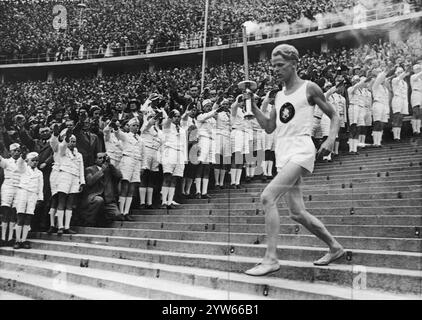 Der deutsche Läufer Erik Schilgen läuft während der Eröffnungszeremonie der Olympischen Spiele in Berlin mit einer Fackel ins Stadion. Archivfoto der Olympischen Sommerspiele 1936 in Berlin Stockfoto