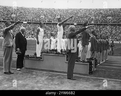 Die Siegermannschaften der Turner auf dem Podium: Deutsche (Goldmedaille), finnische (Silbermedaille) und Schweizer (Bronzemedaille) auf dem Podium. Sichtbar sind: Der Vorsitzende des Berliner Olympischen Organisationskomitees Theodor Lewald (1. Von rechts), der Vorsitzende des Internationalen Olympischen Komitees Henri de Baillet-Latour (2. Von links). Deutsche Athleten mit Nazy-Gruß. Archivfoto der Olympischen Sommerspiele 1936 in Berlin Stockfoto