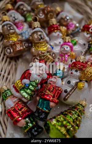 Dekorative Glasornamente in verschiedenen Formen und Farben sind in einer festlichen Präsentation angeordnet. Zu den Ornamenten gehören der Weihnachtsmann, Schneemänner und Weihnachten Stockfoto