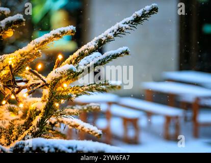 Zauberhafte Winterwunderlandszene auf dem Zürcher Weihnachtsmarkt in der Schweiz mit funkelnden Lichtern und Schneefall, Bänken und Tischen mit Schnee, keine Leute Stockfoto