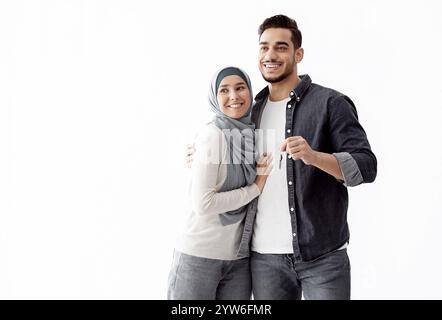 Glückliches muslimisches Paar posiert in leerer Wohnung und zeigt den Schlüssel Stockfoto