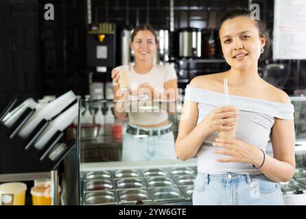 Junge Frau trinkt im Café Sprudeltee Stockfoto