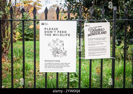 London, UK - 17. November 2024: Hyde Park , Poster von Winter Wonderland vom 21. november 2024 bis 5. januar 2025 auf dem Zaun und ein Poster, das vor der Fütterung von Wildtieren warnt. Stockfoto