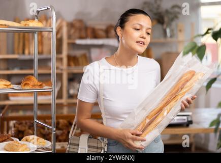 Asiatische Frau, die ein Baguette in den Händen hält Stockfoto