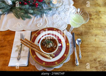 Enteneintopf und Brotstangen auf feinem Porzellan stellen Platz auf einem Weihnachtstisch. Stockfoto