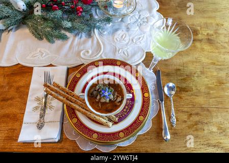 Enteneintopf und Brotstangen auf feinem Porzellan stellen Platz auf einem Weihnachtstisch. Stockfoto