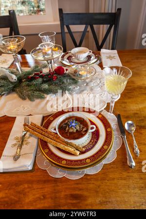 Enteneintopf und Brotstangen auf feinem Porzellan stellen Platz auf einem Weihnachtstisch. Stockfoto