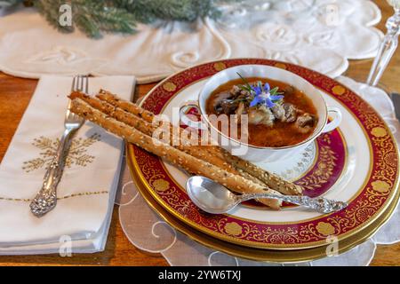 Enteneintopf und Brotstangen auf feinem Porzellan stellen Platz auf einem Weihnachtstisch. Stockfoto