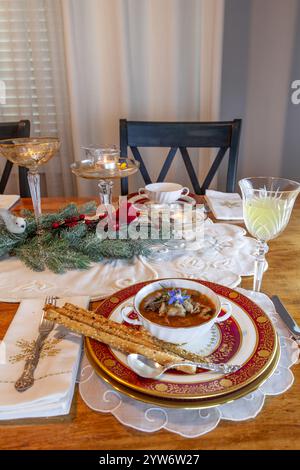 Enteneintopf und Brotstangen auf feinem Porzellan stellen Platz auf einem Weihnachtstisch. Stockfoto