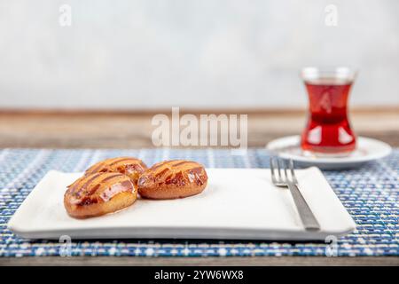 Traditionelles türkisches Dessert mit Tee: Sekerpare. Sekerpare wird mit Tee auf einem weißen Teller serviert. Stockfoto