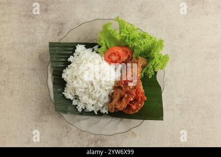 Top View Nasi Ayam Penyet oder Penyetan Ayam, Indonesisch scharfes Huhn mit verschiedenen Gemüsesorten Stockfoto
