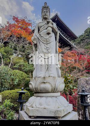 Ruhige Kannon-Statue inmitten von Herbstlaub in einem japanischen Tempel Stockfoto