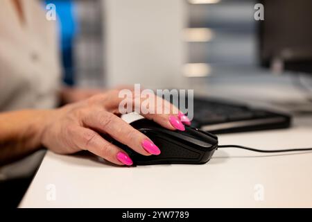 Weibliche Hände tippen auf einer schwarzen Computertastatur in einem modernen Büro. Großaufnahme weiblicher Hände mit einer Computermaus im Büro. Stockfoto