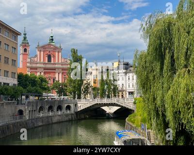 Ljubljana, Slowenien - 28. Juni 2024: Rot-rosa historische Franziskanerkirche der Verkündigung monumentale Fassade mit Statue. Aus Sicht von Acro Stockfoto