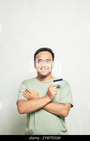 Muskulöser asiatischer Mann im hellgrünen Hemd, der Karten auf weißem Hintergrund hält Stockfoto