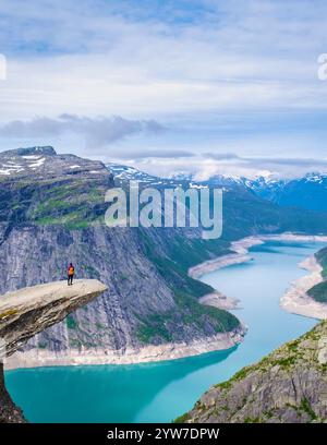 Eine einsame Wanderer steht am Rande von Trolltunga, Norwegen, einer dramatischen Klippe mit Blick auf einen türkisfarbenen Fjord in Norwegen. Die Weite der Landschaft Stockfoto