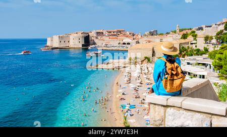 Ein Reisender blickt auf die glitzernde Adria von einem malerischen Aussichtspunkt und bewundert die historischen Mauern von Dubrovnik. Asiatische Frauen mit Hut und Rucksack Stockfoto