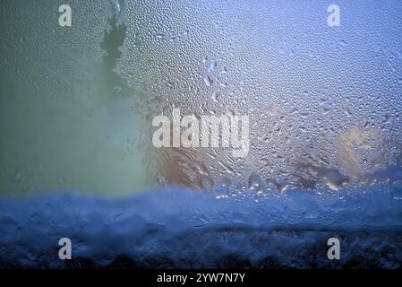 Eine detaillierte Ansicht der kondensierten Wassertropfen an einem Fenster, die kalte Wintermorgen, Frost und Wettermuster darstellen. Das Bild erweckt ein Gefühl von t Stockfoto