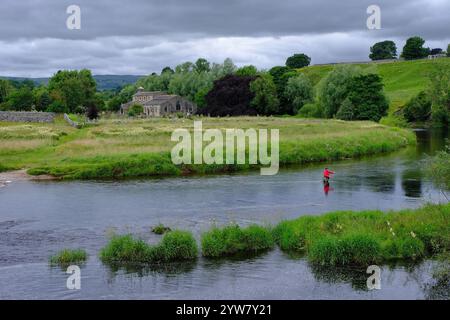 Linton: Fliegenfischer, die Ruten in River Wharfe und St Michael und All Angels Church in Linton, Grassington, Wharfedale, North Yorkshire, England Stockfoto