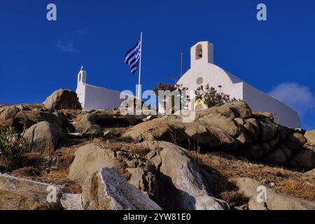 IOS: Agios Georgios Kapelle mit Mosaiken und Agios Nikolaos Kapelle mit griechischer Flagge auf dem felsigen Hügel von iOS (IO) Chora Stadt, iOS, Kykladen Insel, Griechenland Stockfoto