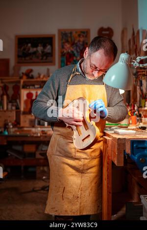 Cremona, Italien - 9. Dezember 2024 - Luca Tenore Meister des Geigenbauers, der in seiner Werkstatt sorgfältig an einer Geige arbeitete, mit Präzision und Expertise Stockfoto