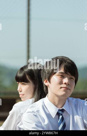 Weibliche und männliche Schüler sitzen Rücken an Rücken Stockfoto