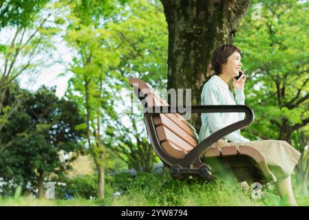 Eine junge Frau, die im Park telefoniert Stockfoto