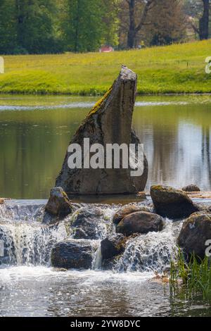 Ruhiger Fluss mit kaskadierendem Wasser über Felsen in einer üppigen grünen Landschaft Stockfoto