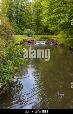 Kleiner Wasserfall in einem ruhigen Waldteich umgeben von üppigem Grün Stockfoto