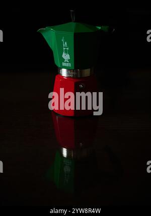 Italienische Espressomaschine in Grün und Rot mit markanter Reflexion auf dunkler Oberfläche, die ein klassisches Küchenthema einfängt. Stockfoto
