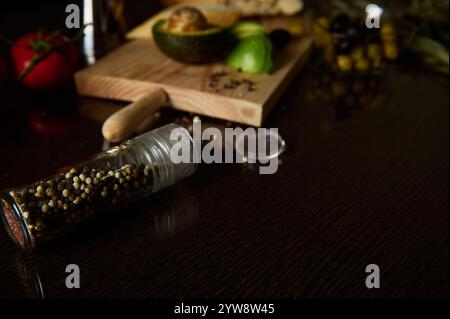 Eine rustikale Küchenszene mit Pfefferstreuer, frischer Avocado und Gewürzen. Warme, einladende Atmosphäre, perfekt für kulinarische Inspiration und Gourmet-Co Stockfoto