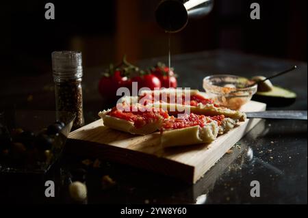 Hausgemachte Bruschetta mit frischen Tomaten auf einem Holzbrett, umgeben von Zutaten. Stockfoto