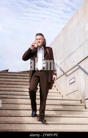 Reifer Geschäftsmann, der die Treppe hinunter läuft Stockfoto