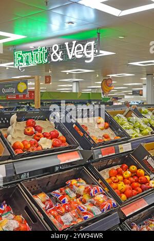 Ein Schild mit Obst- und Gemüsebeleuchtung an der Decke über Kunststoffkisten mit roten und grünen Äpfeln zum Verkauf oder Großpackungen Essex England UK Stockfoto