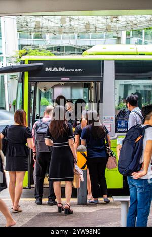 An Wochentagen warten Pendler auf einen gelben Bus an einer Bushaltestelle im Zentrum von Singapur Stockfoto