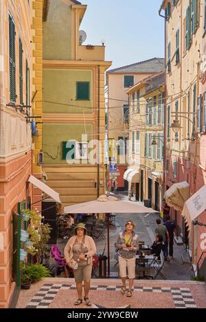 Savona. Italia - 10. Dezember 2024: Eine typisch italienische Straße mit farbenfrohen Gebäuden, einem Café im Freien und Spaziergängen fängt das tägliche Leben und ein Stockfoto