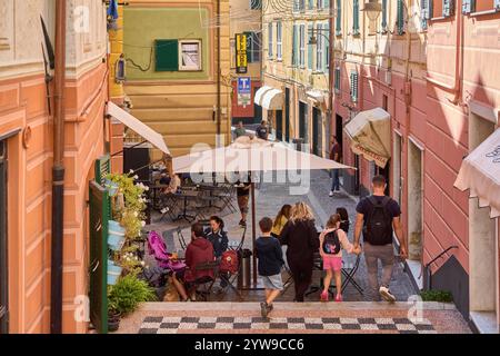 Savona. Italia - 10. Dezember 2024: Fußgängerzone mit farbenfrohen Gebäuden und Cafés im Freien fängt die lebhafte Atmosphäre ein, in der Einheimische und Touren stattfinden Stockfoto