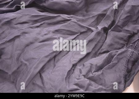 Ungewöhnliche Stoffe, sehr zerknittert, seidendünn, dunkelblaue Baumwolle, Viskose befindet sich auf weißem Kunststoffhintergrund. Stockfoto