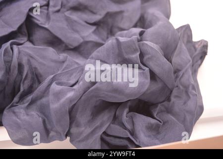 Ungewöhnliche Stoffe, sehr zerknittert, seidendünn, dunkelblaue Baumwolle, Viskose befindet sich auf weißem Kunststoffhintergrund. Stockfoto