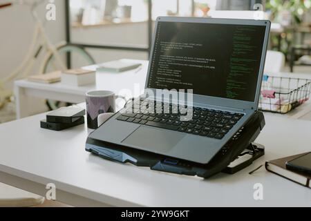 Mittlere Nahaufnahme eines Laptops mit Codes auf dem Kühlkissen in leerem Büro der IT-Firma Stockfoto
