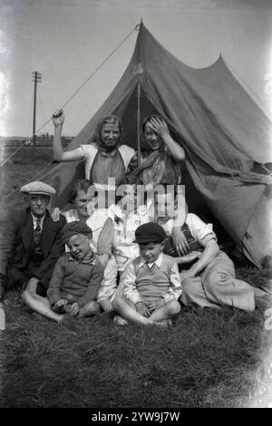 1930er Jahre, historisch, eine Familie versammelt sich für ein Foto vor ihrem Ferienheim Ein traditionelles Zeltdach aus Segeltuch Anzug & Krawatte und weit flach auf dem älteren Mann, während die beiden Jungen vorne beide Kappen tragen, England, UK. Zwei junge Mädchen stehen aufgeregt hinten. Stockfoto